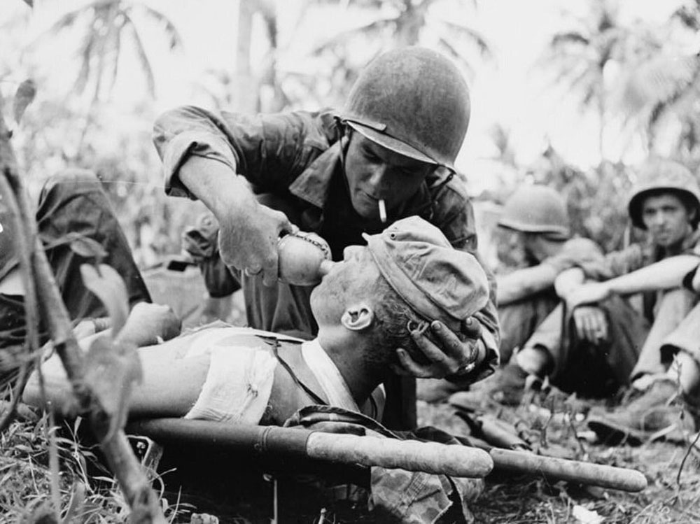 ทหารนาวิกโยธินมอบน้ำให้กับนาวิกโยธินที่ได้รับบาดเจ็บหลังจากการต่อสู้อย่างดุเดือดในเกาะกวม