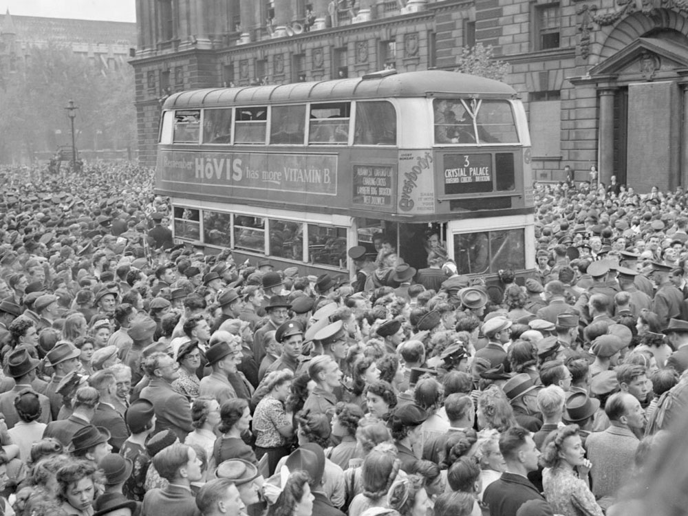 พนักงานบริการและพลเรือนรวมตัวกันเพื่อเฉลิมฉลองในกรุงลอนดอนประเทศอังกฤษเมื่อวันที่ 8 พฤษภาคม 1945 เพื่อฟังสุนทรพจน์แห่งชัยชนะของเชอร์ชิลล์