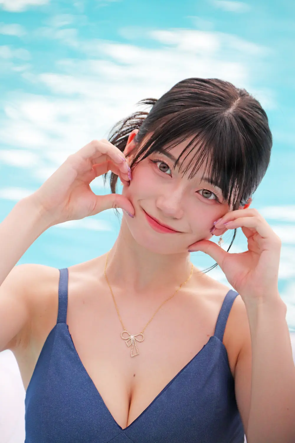 Kanna Seto สวมชุดว่ายน้ำสีน้ำเงินและวางมือข้างใบหน้า
