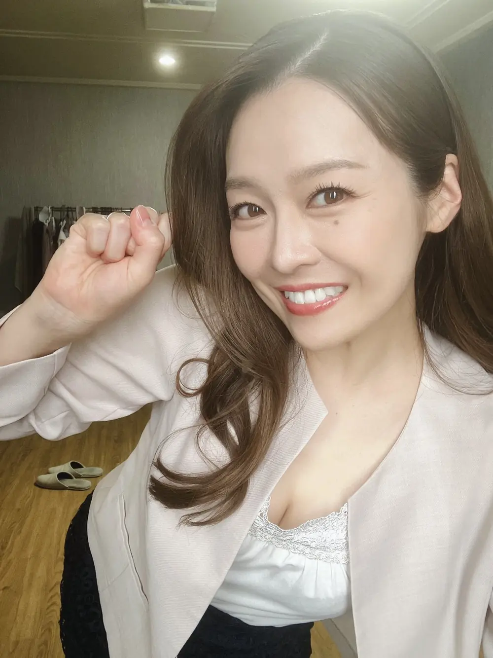 Kanna Fuji สวมเสื้อคลุมสีอ่อนและยิ้มให้กล้อง