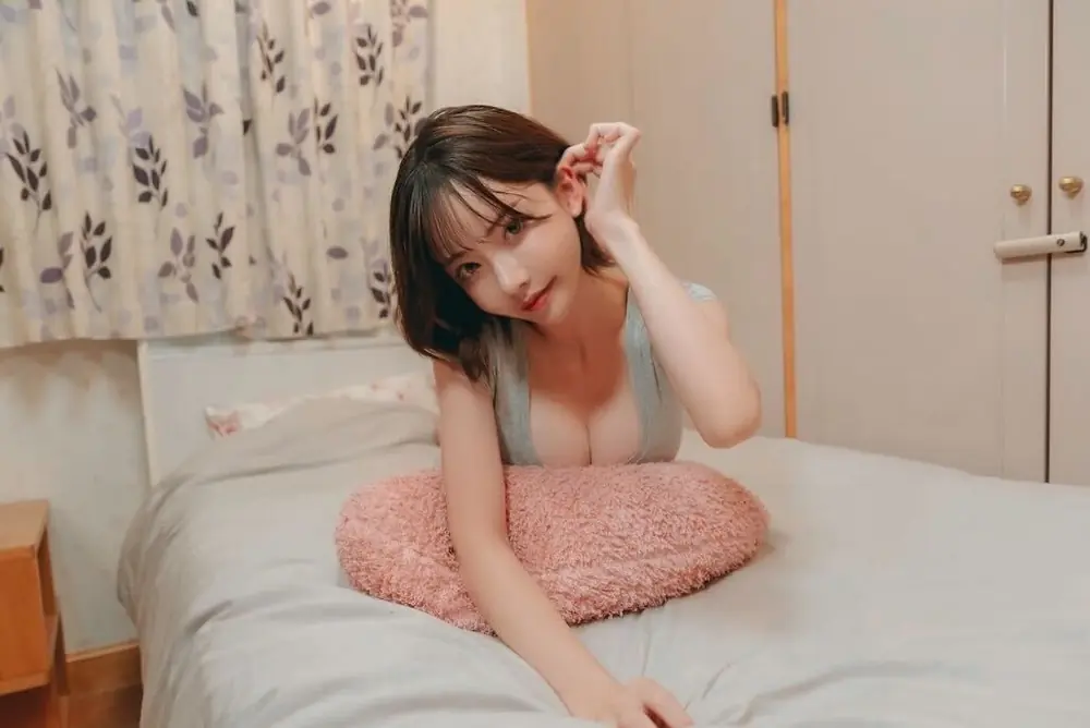 Eimi Fukada เอนตัวบนหมอนสีชมพูในห้องนอน
