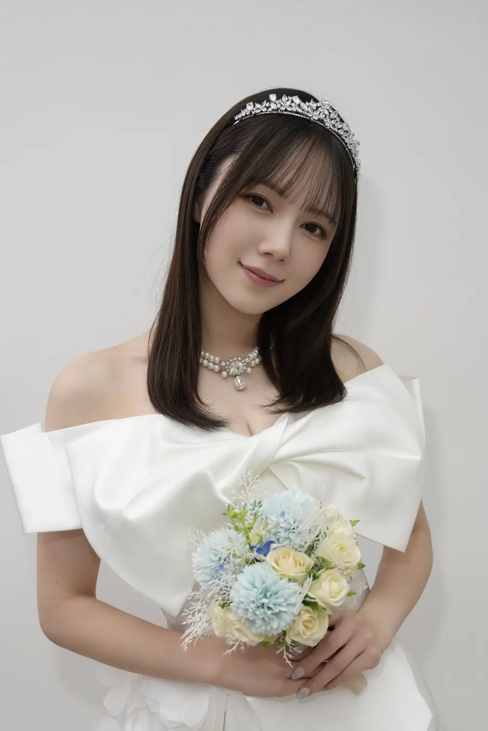 Remu Suzumori สวมชุดสีขาวและถือช่อดอกไม้