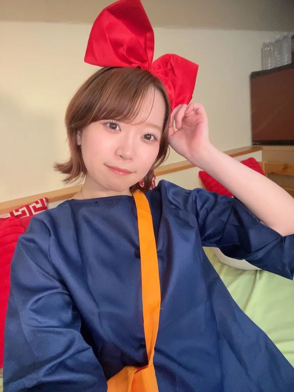 Yura Kano สวมชุดสีน้ำเงินและที่คาดผมโบสีแดงขนาดใหญ่