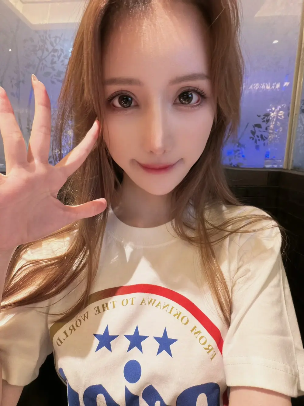 Karen Yuzuriha สวมเสื้อยืดสีขาวและยกมือทักทายกล้อง