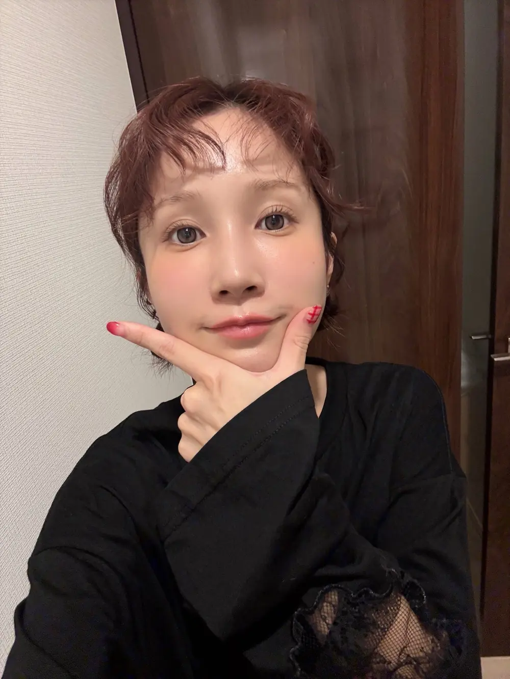 Minami Kojima สวมเสื้อแขนยาวสีดำและวางมือใต้คาง