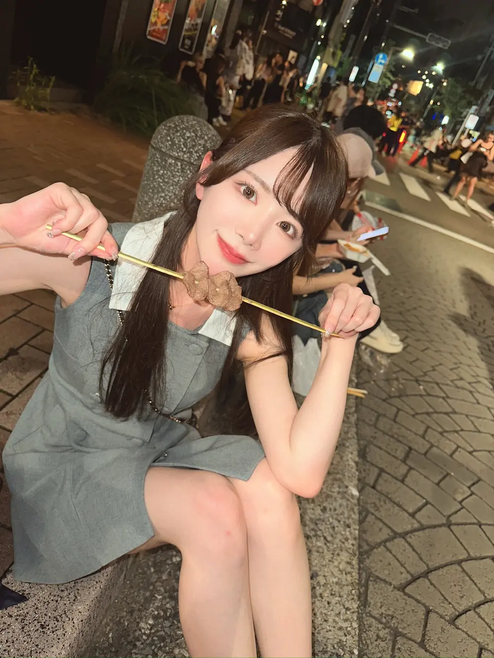 Mirei Uno ถืออาหารเสียบไม้บนถนนยามค่ำคืน