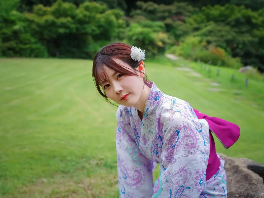 Sakura Miura สวมชุดยูกาตะลายสีม่วงยืนอยู่ในสวนสีเขียว