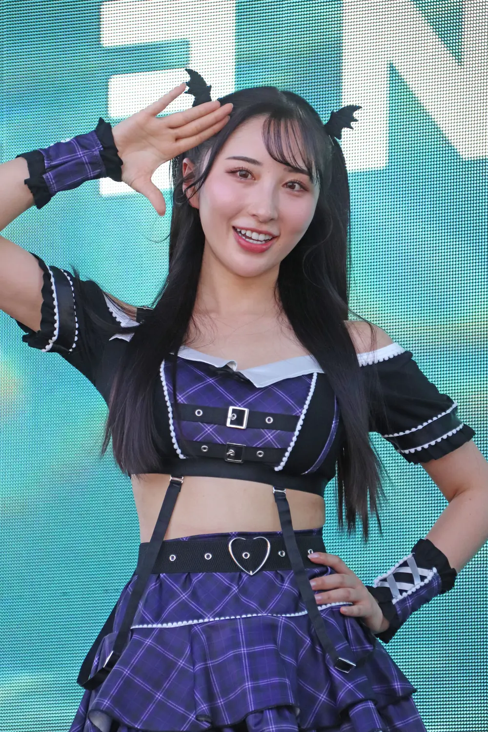 Mina Kitano สวมชุดคอสเพลย์สีม่วงดำและยกมือข้างศีรษะ