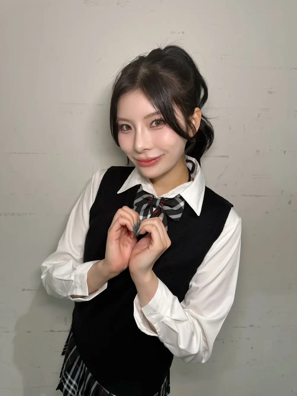 Rei Kamiki สวมเสื้อเชิ้ตสีขาวกับเสื้อกั๊กสีดำและทำมือรูปหัวใจ