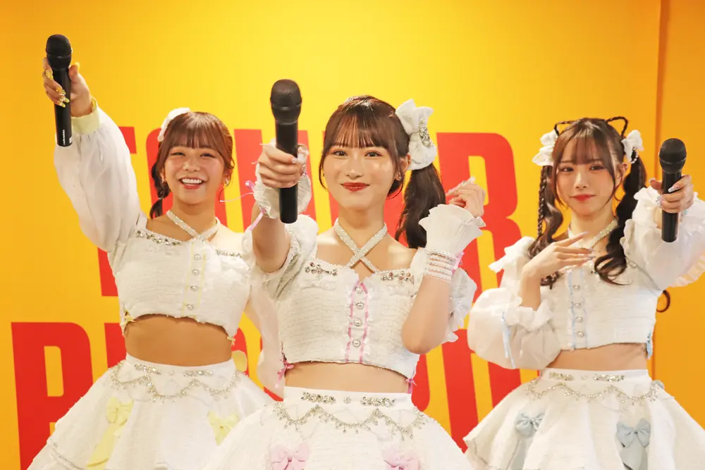 Saki Sasaki ร่วมแสดงกับสมาชิกวงในชุดสีขาวและถือไมโครโฟนบนเวที