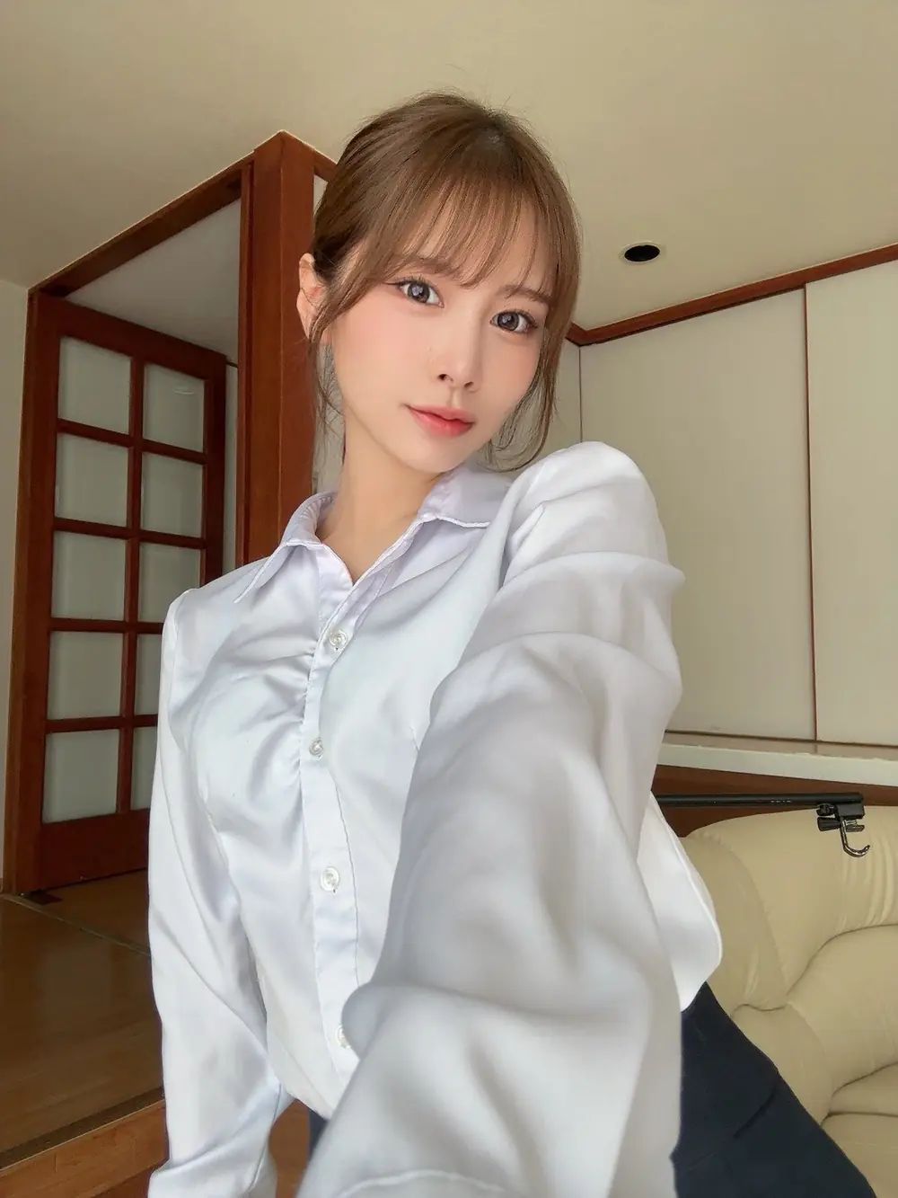 Miyu Otori สวมเสื้อเชิ้ตสีอ่อนและมองกล้องในห้อง