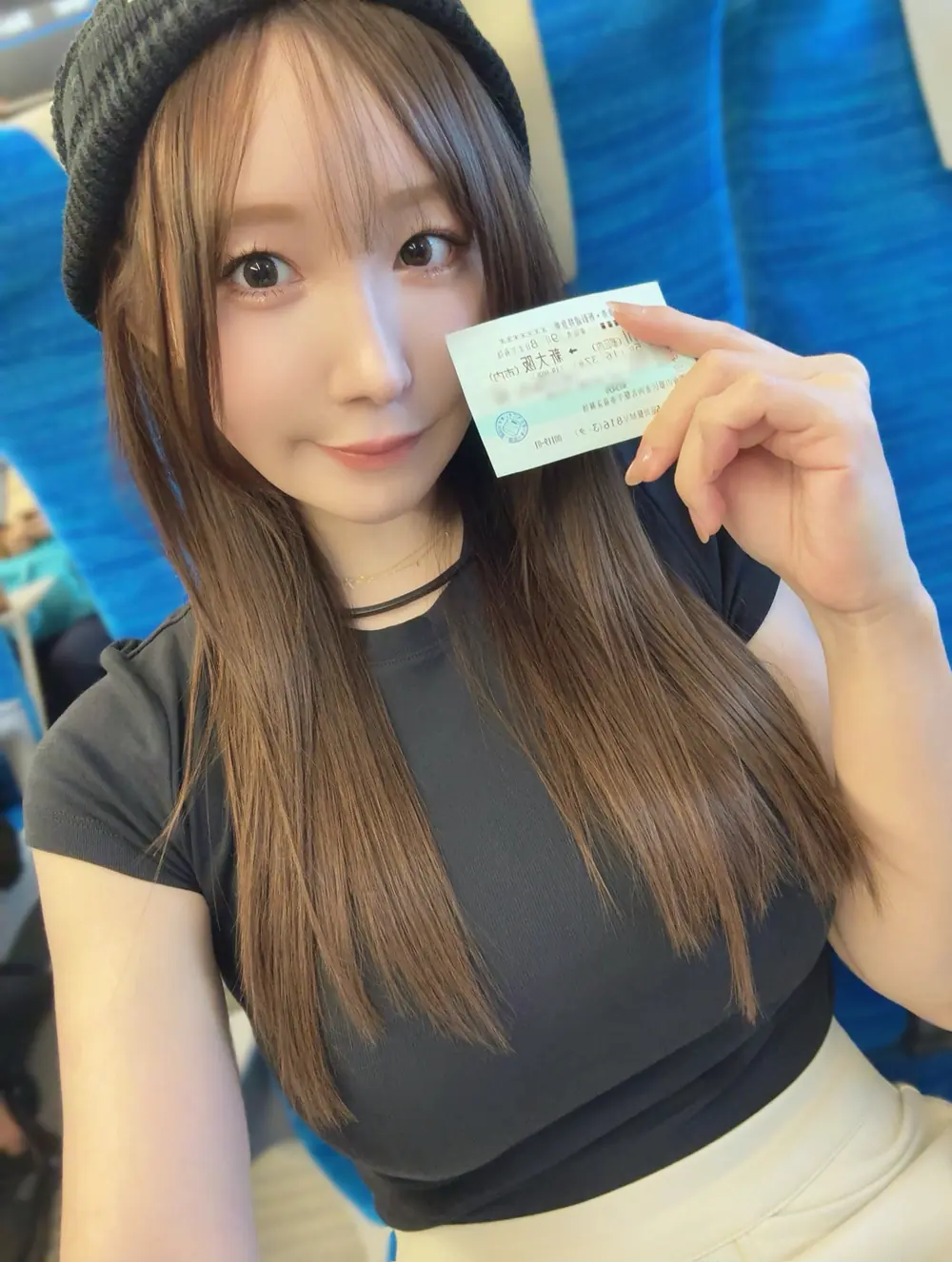 Goddess Jun สวมหมวกสีดำและถือบัตรโดยสารขณะนั่งบนรถไฟ