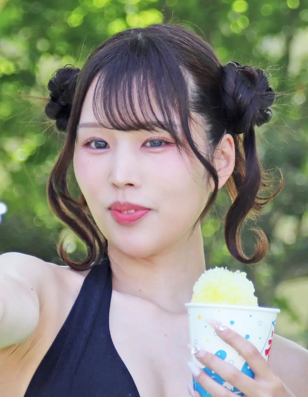 Rima Arai ถือถ้วยน้ำแข็งไสสีเหลืองในงานถ่ายภาพกลางแจ้ง