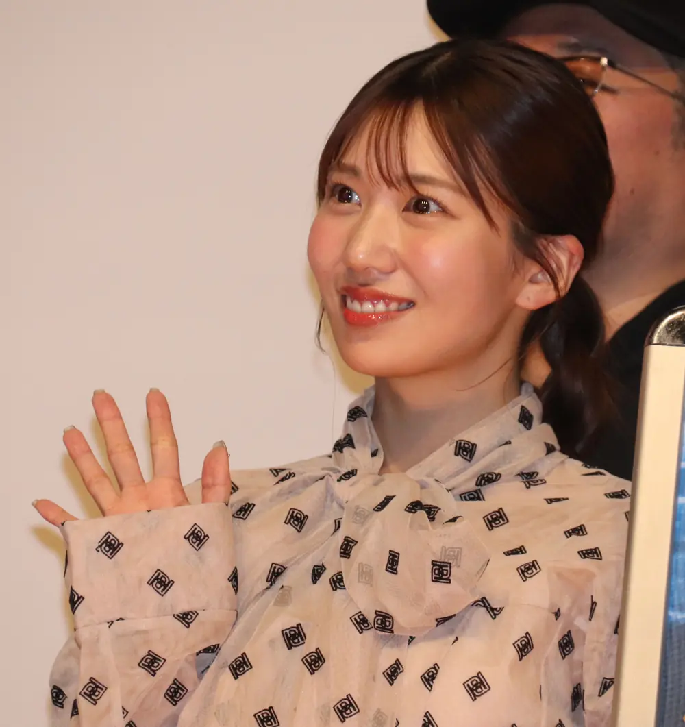 Aika Yamagishi สวมเสื้อสีอ่อนลายสีดำและยิ้มให้ผู้ชม