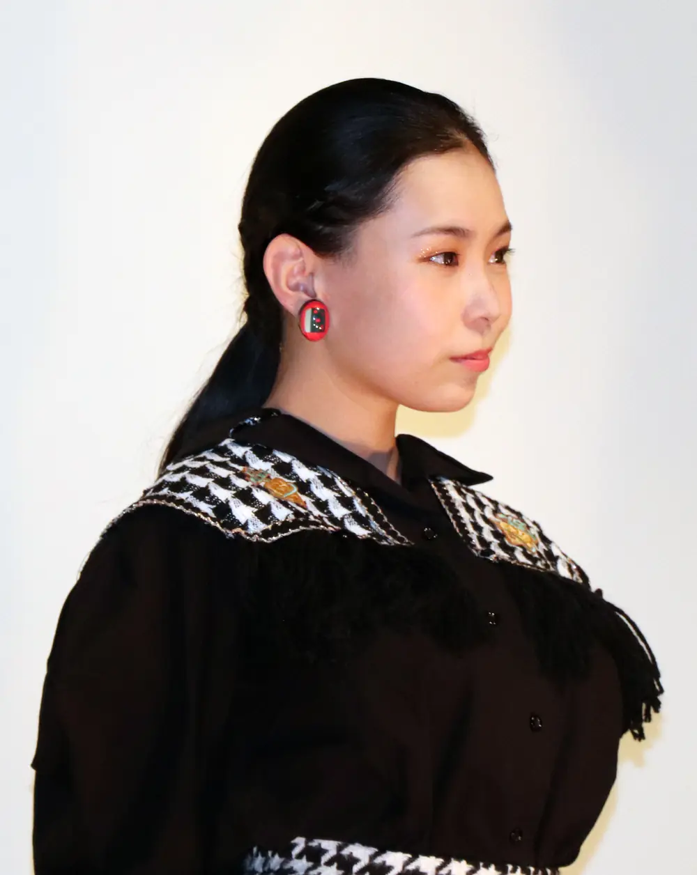Julia Yoshine สวมเสื้อสีดำแต่งปกลายขาวดำและต่างหูสีแดง