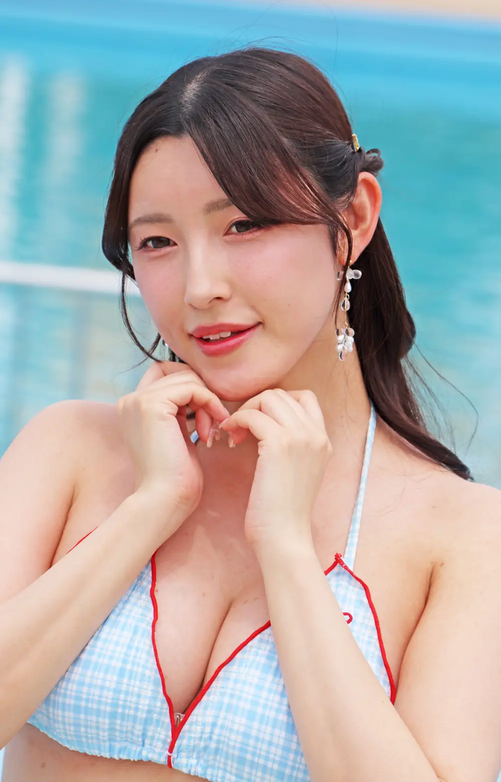 Kana Morisawa สวมชุดว่ายน้ำลายตารางสีฟ้าขอบแดงและวางมือใต้คาง