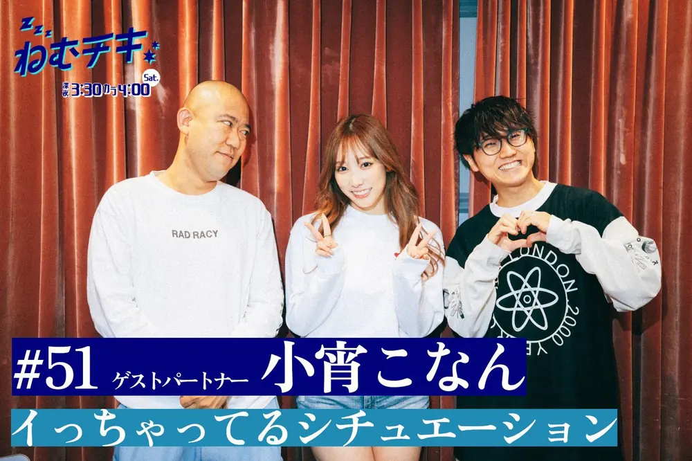 Konan Koyoi สวมเสื้อสีขาวและชูสองนิ้วขณะถ่ายภาพร่วมกับพิธีกรสองคน