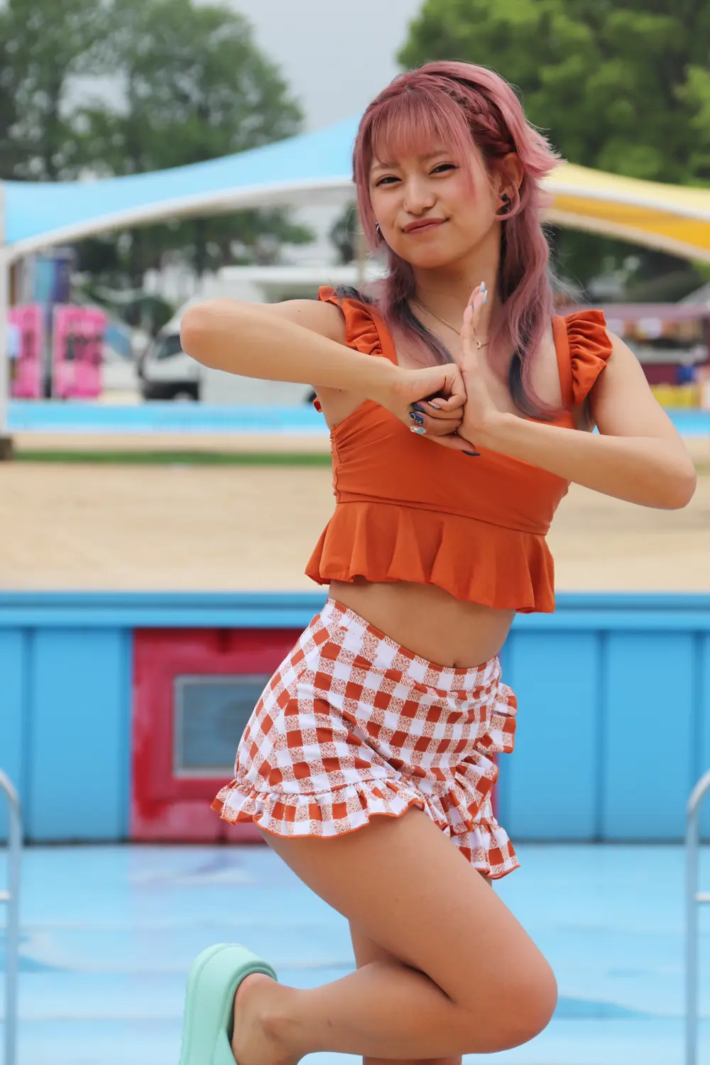 Mitsuki Nagisa สวมชุดว่ายน้ำสีส้มและกระโปรงลายตารางที่สวนน้ำ