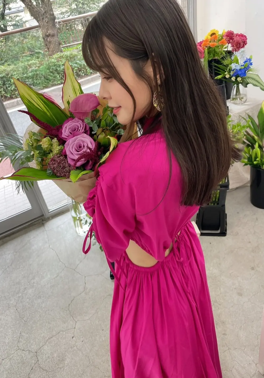 Nana Yagi สวมชุดสีชมพูเข้มและถือช่อดอกไม้ในห้องจัดแสดง