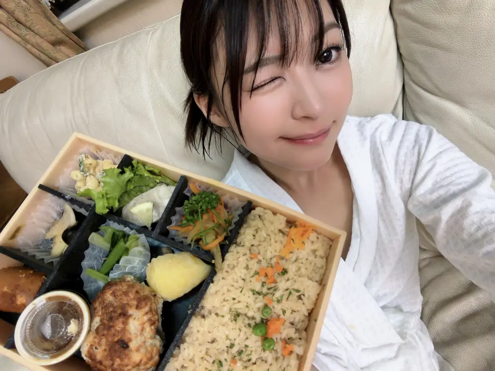 Natsu Tojo สวมเสื้อสีขาวและถือกล่องอาหารพร้อมขยิบตา