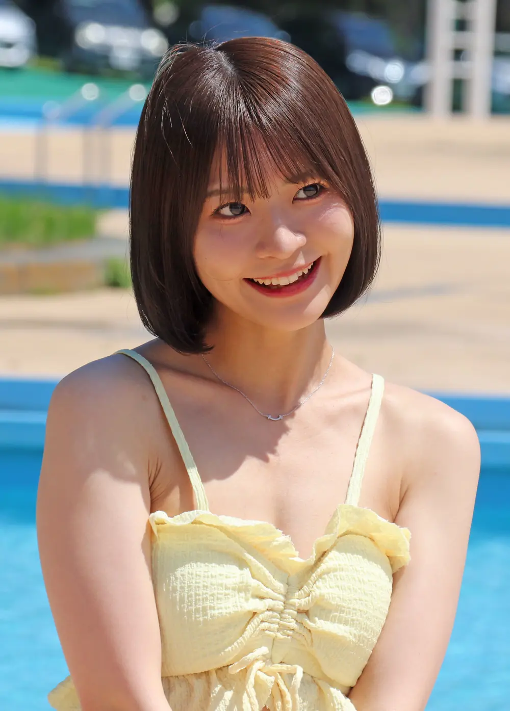 Natsu Tojo สวมชุดว่ายน้ำสีเหลืองอ่อนและยิ้มริมสระ