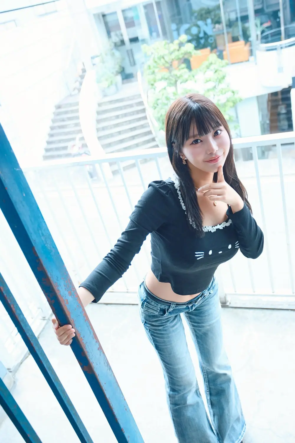 Yua Fukuda สวมเสื้อสีดำและกางเกงยีนส์ยืนข้างประตูกระจก