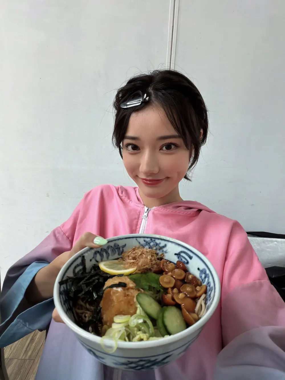 Rena Miyashita สวมเสื้อสีชมพูและถือชามอาหาร