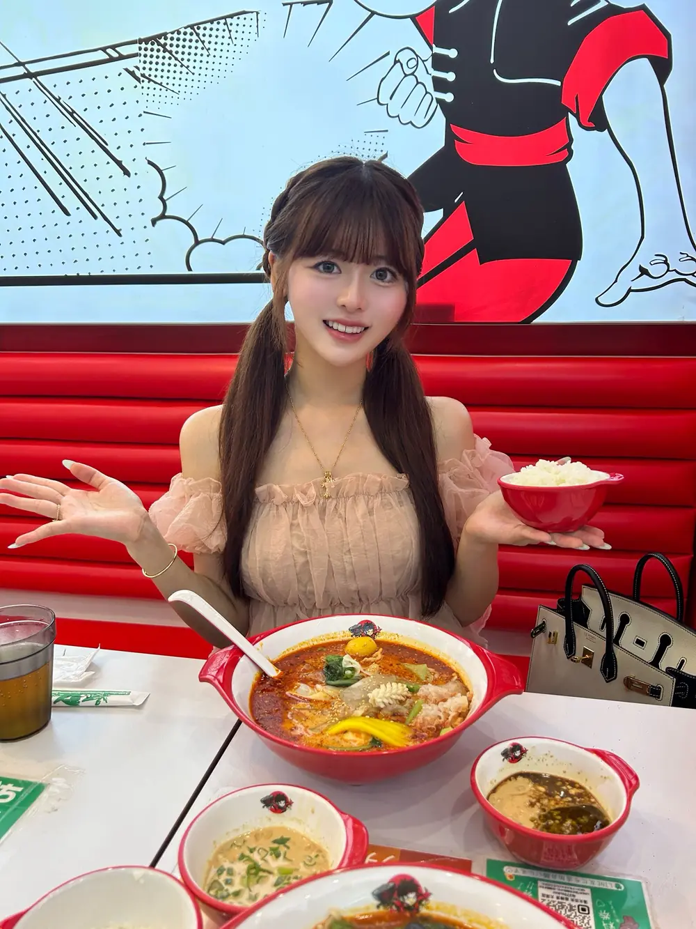 Rino Sakurano นั่งหน้าอาหารในร้านที่มีเบาะสีแดง