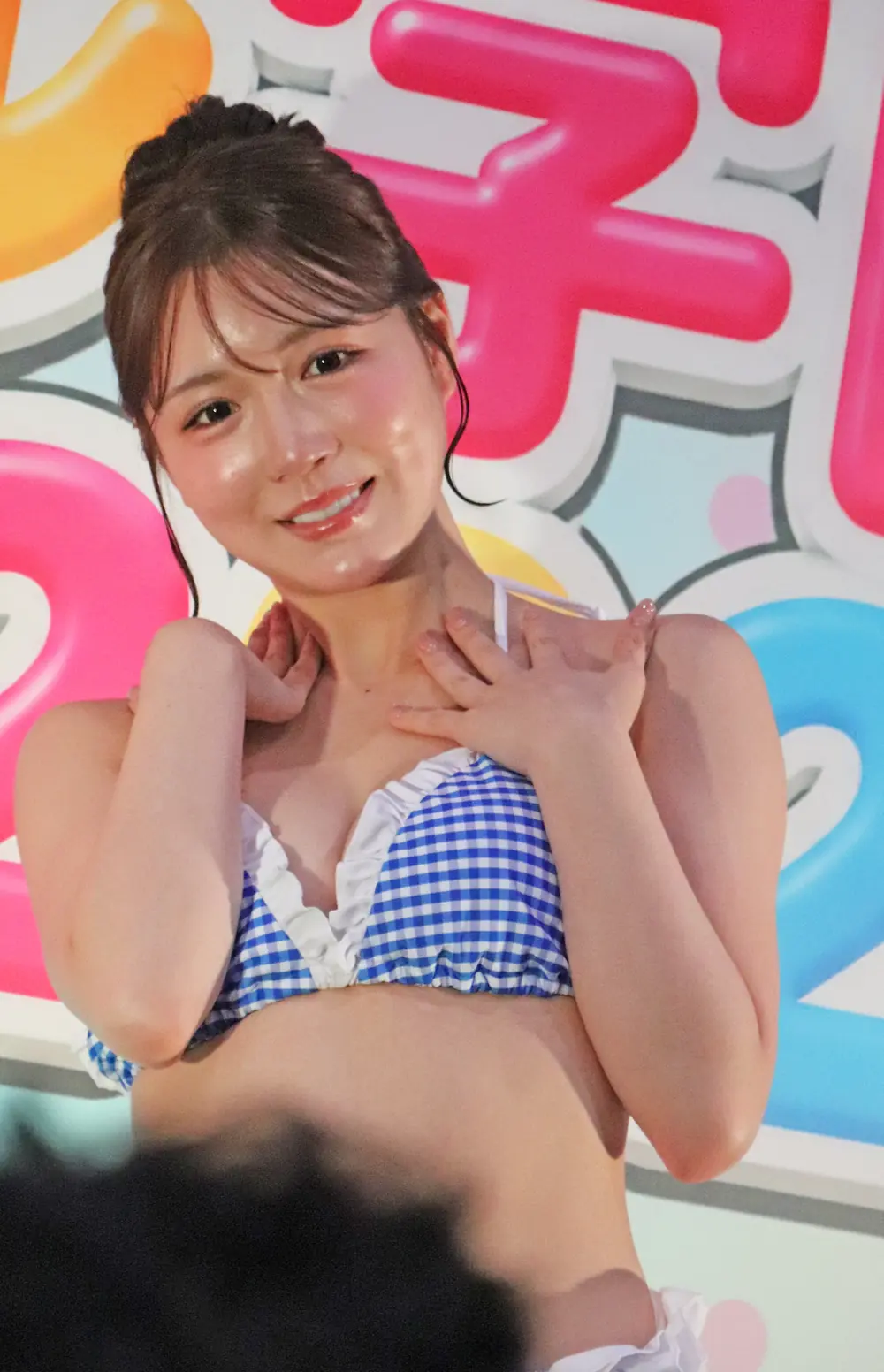 Saho Shinozaki สวมชุดว่ายน้ำลายตารางสีน้ำเงินและยิ้มหน้าฉากงาน