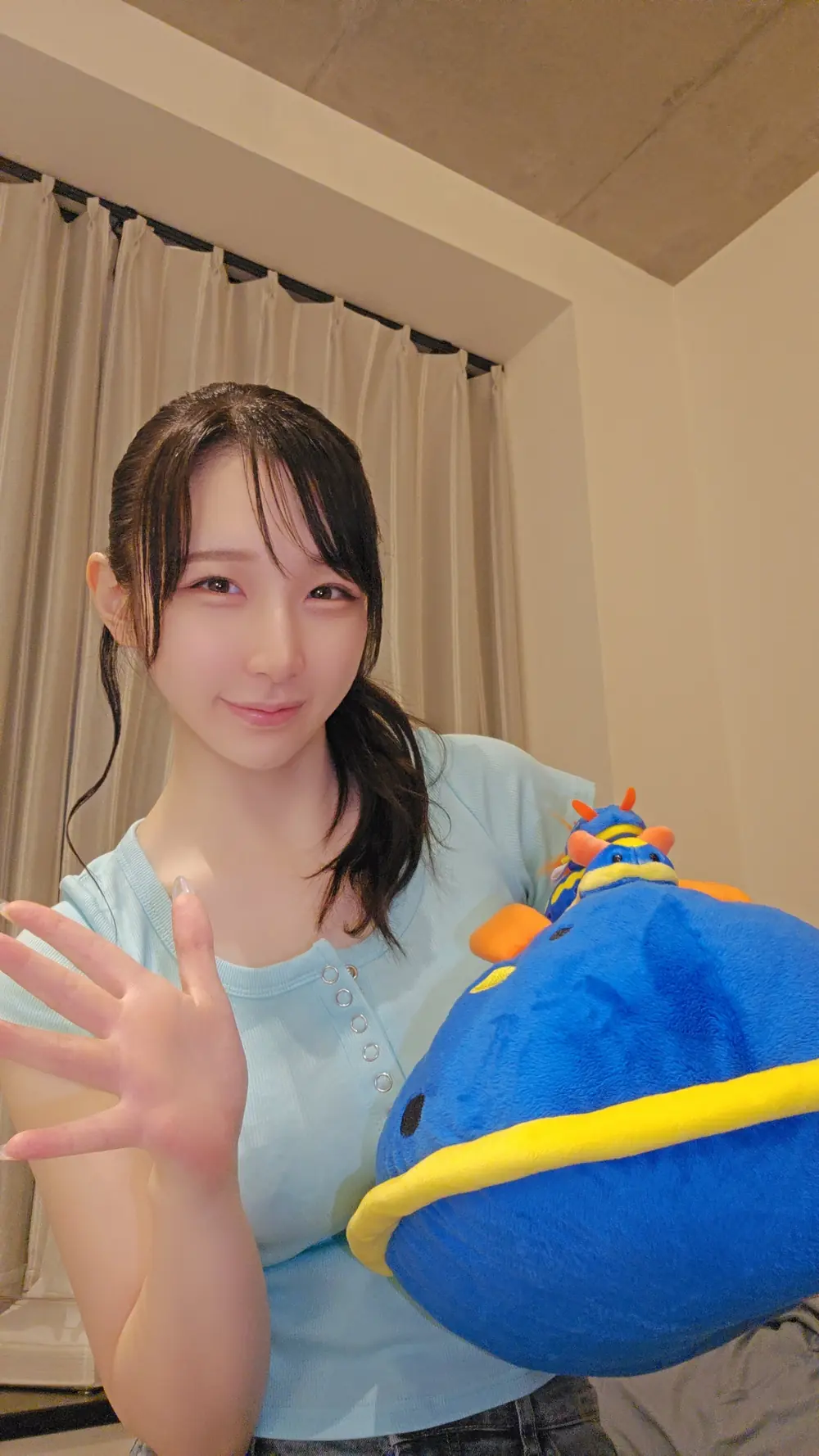 Sora Komatsu สวมเสื้อสีฟ้าและถือตุ๊กตาสีน้ำเงิน