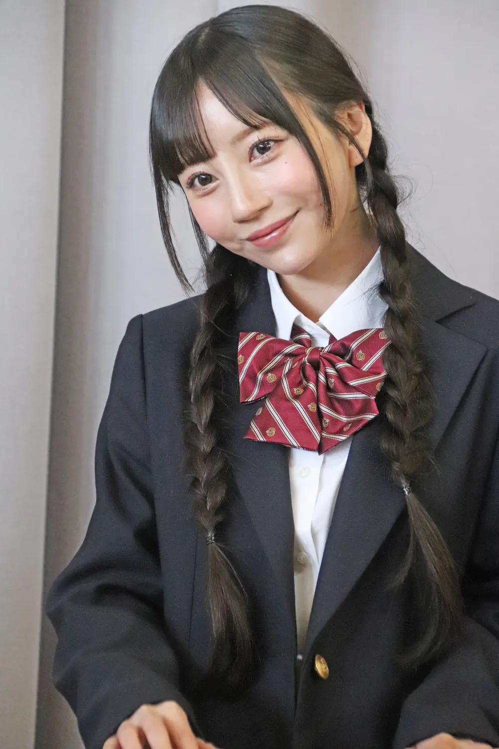 Mia Nanasawa ถักเปียสองข้าง สวมเสื้อแจ็กเก็ตสีเข้มและโบสีแดง