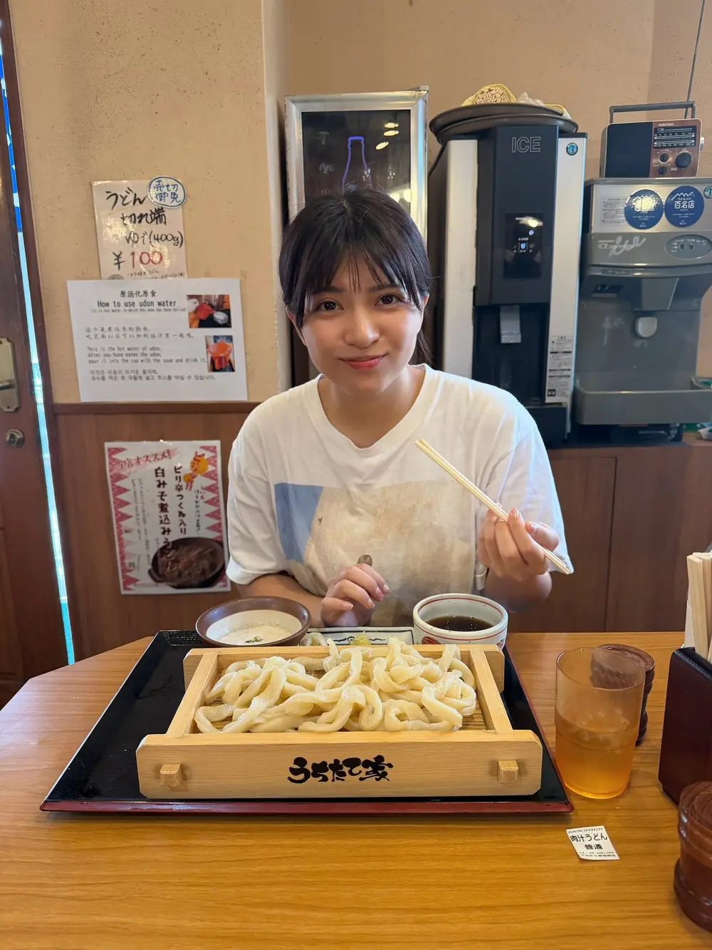 Akari Neo สวมเสื้อสีขาวนั่งหน้าอาหารอุด้งในร้าน