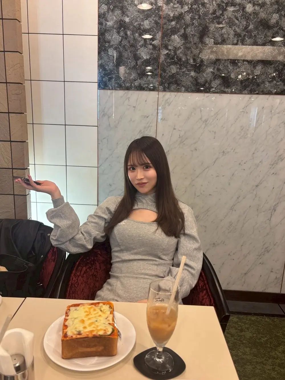Miina Tsuji นั่งอยู่ในร้านอาหารและยิ้มให้กล้อง โดยมีอาหารกับเครื่องดื่มอยู่บนโต๊ะ