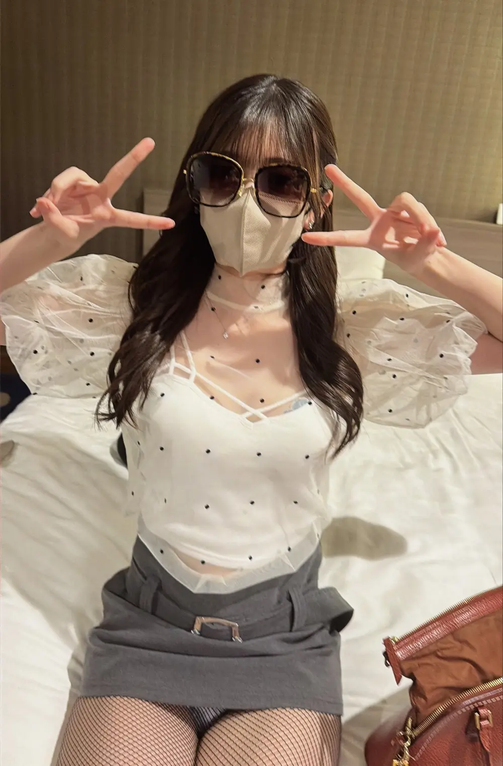 Iori Kitano สวมแว่นกันแดด เสื้อสีขาวลายจุด และกางเกงสีเทา