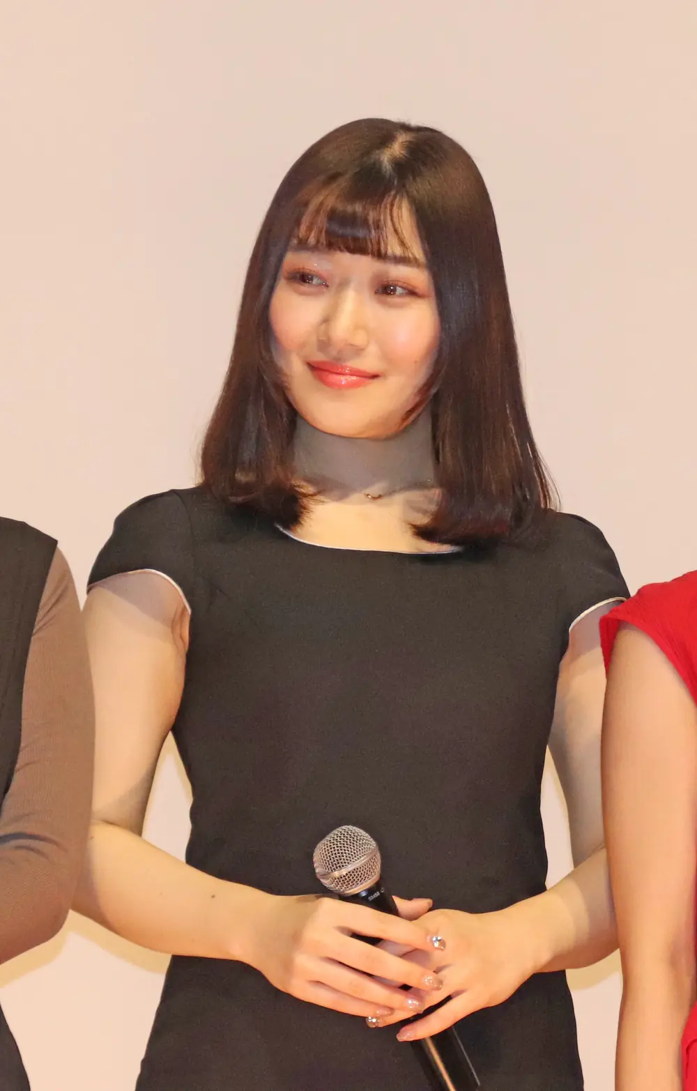 Ena Koume สวมเดรสสีดำและถือไมโครโฟนขณะร่วมงานภาพยนตร์