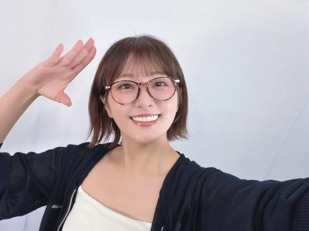 Hikari Aozora สวมแว่นตาและเสื้อคลุมสีเข้มยิ้มให้กล้อง