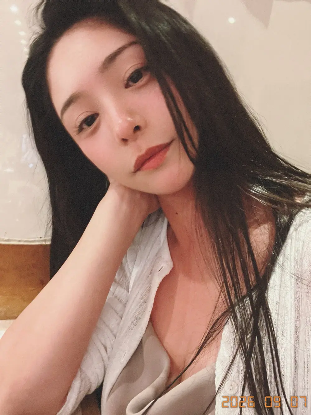 Meguri สวมเสื้อสีอ่อนนั่งเท้าคางในห้อง