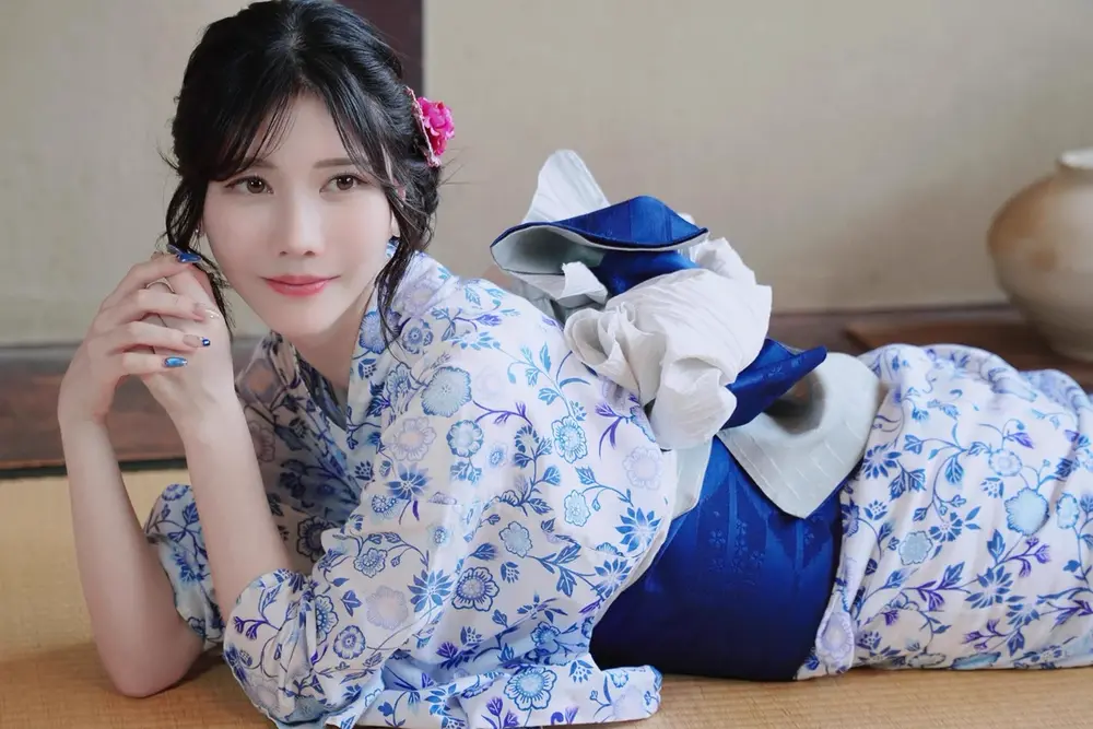 Mizuki Aiga สวมชุดลายดอกไม้สีน้ำเงินนอนอยู่ในห้อง