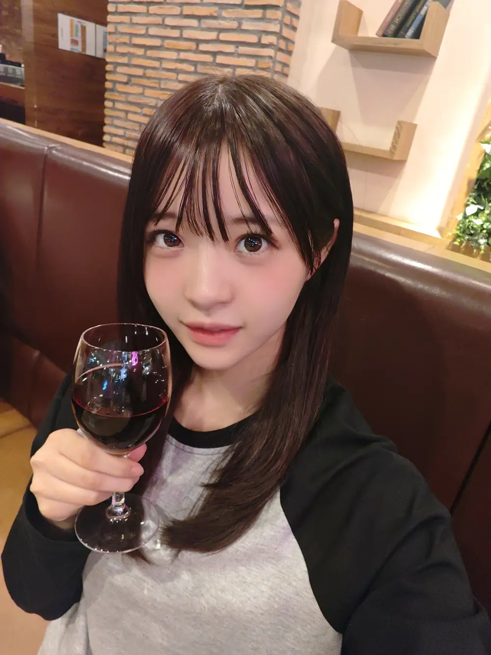 Momo Inoue สวมเสื้อสีดำเทาถือแก้วขณะนั่งในร้านอาหาร