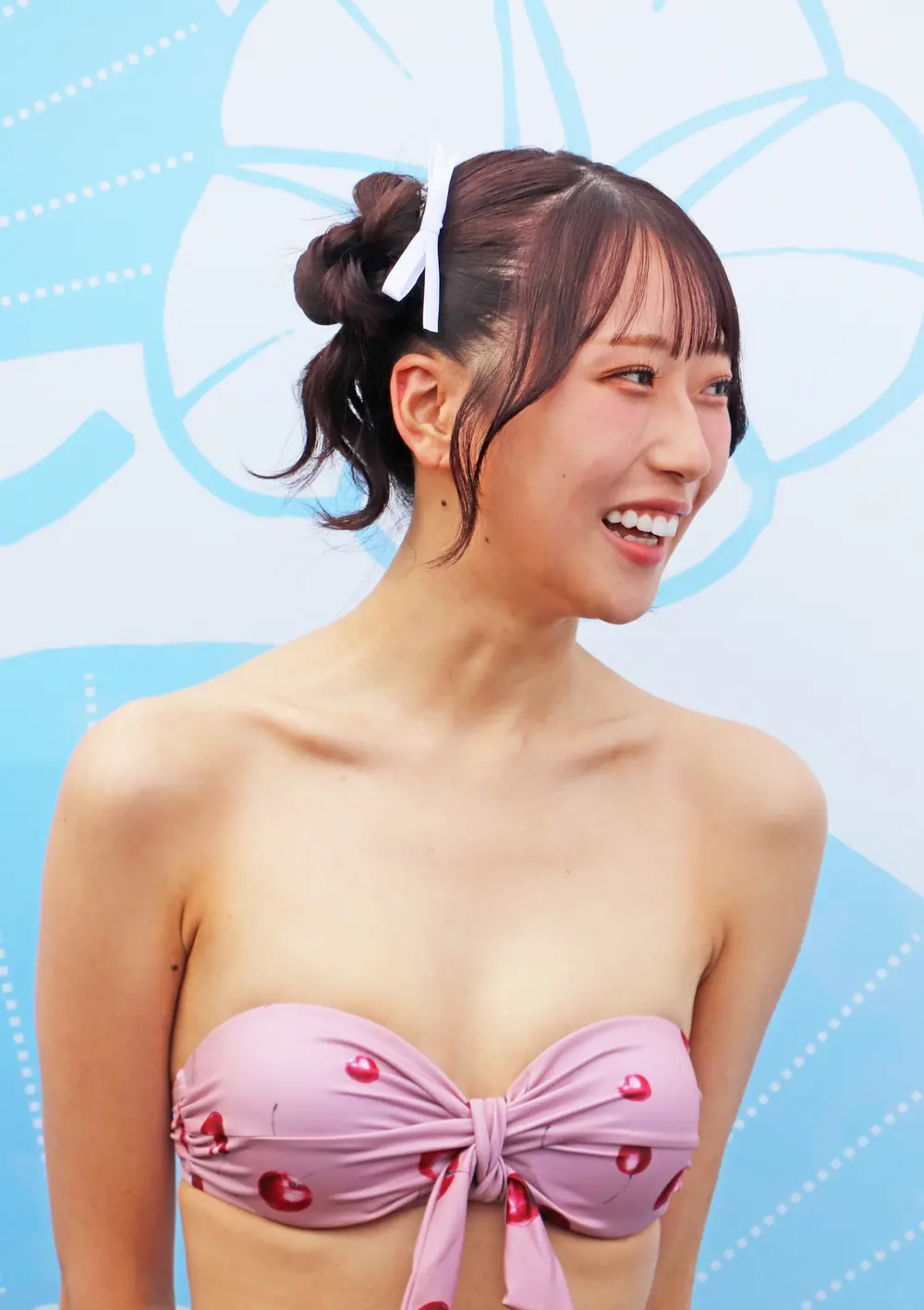 Ui Amagami สวมชุดว่ายน้ำสีชมพูลายเชอร์รีและหันมายิ้ม