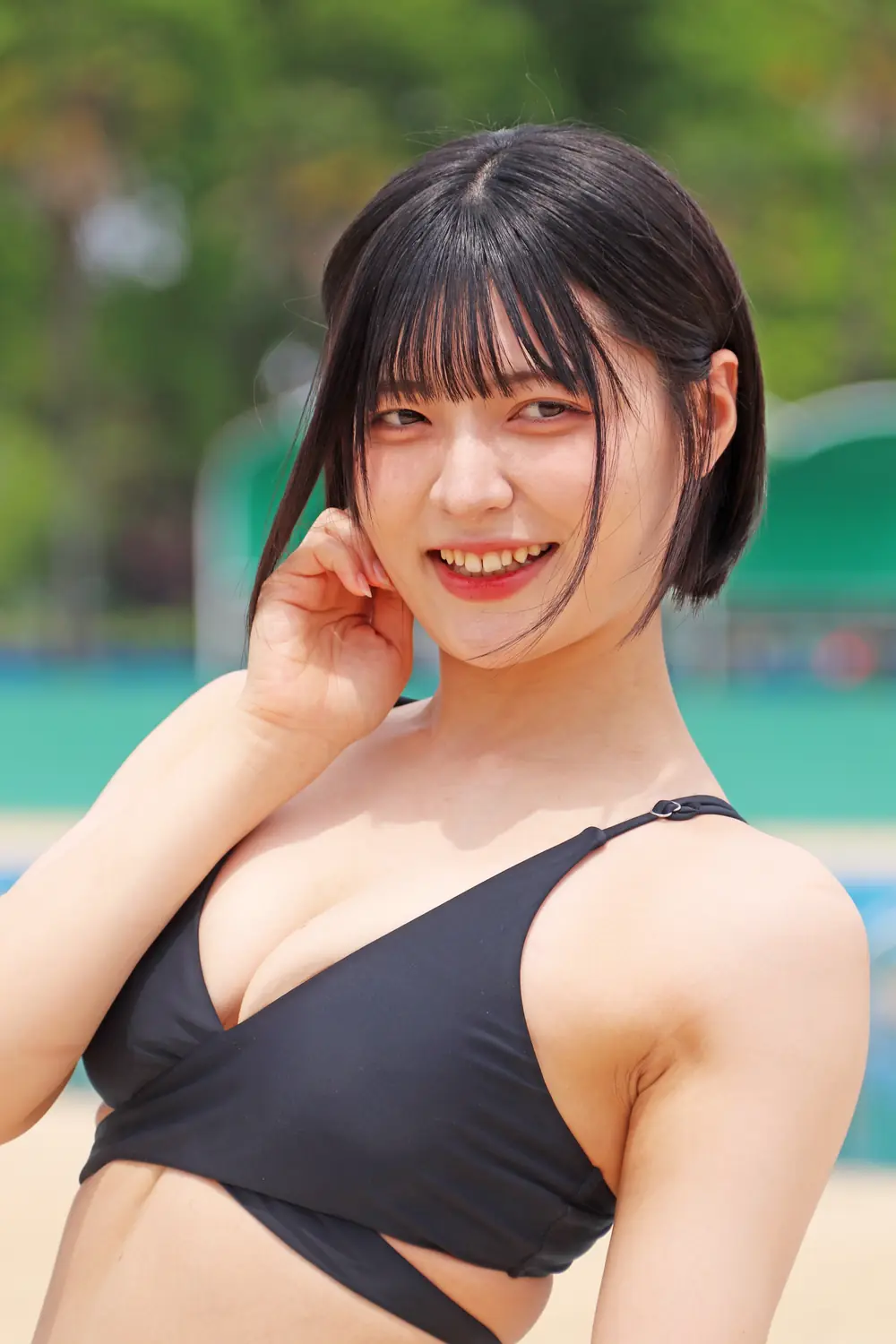Yumi Nijimura สวมชุดว่ายน้ำสีดำและยิ้มขณะยกมือแตะข้างใบหน้า