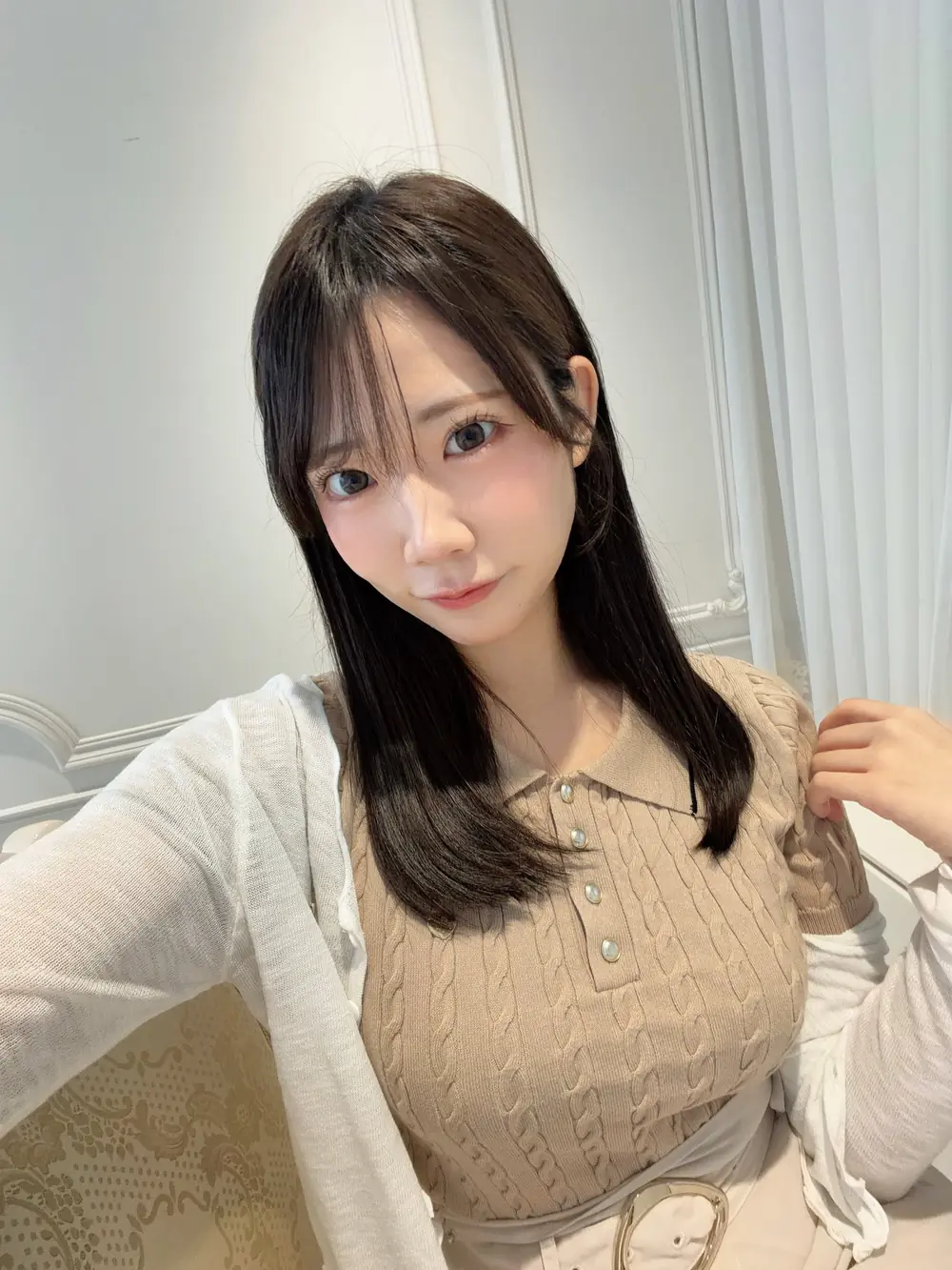 Yuno Sakura สวมเสื้อสีเบจและเสื้อคลุมสีขาว
