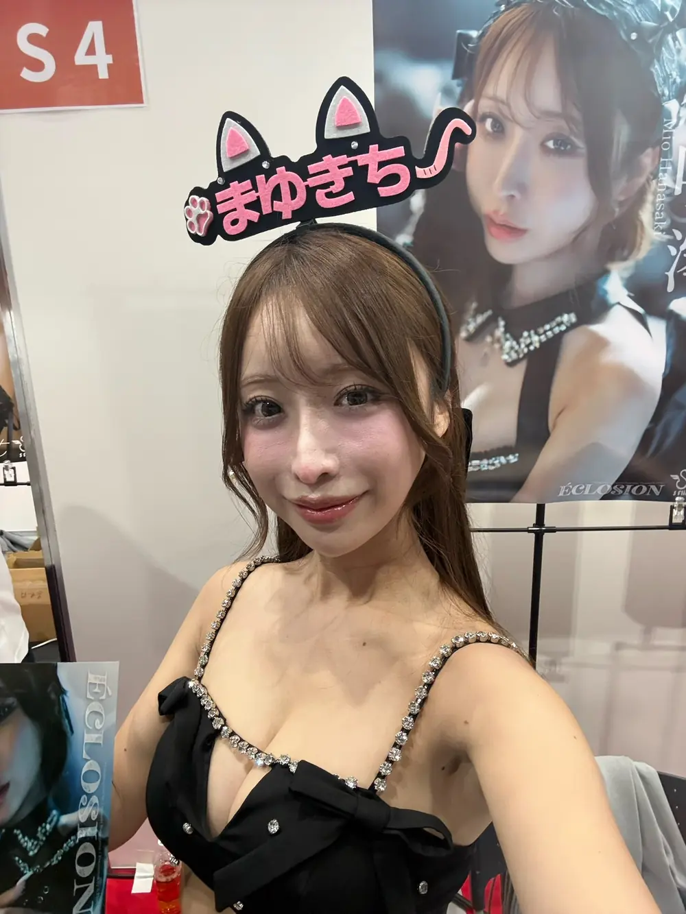 Mio Hanasaki สวมชุดสีดำประดับโบและที่คาดผมตัวอักษรสีชมพูภายในงาน