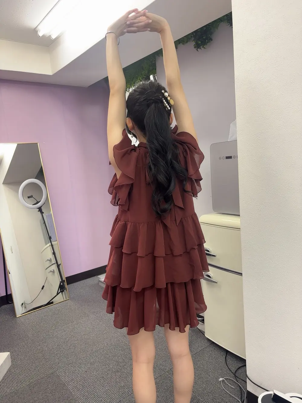 Yuri Yamada ในเดรสสีแดงเข้ม ยืดแขนเหนือศีรษะในห้องพักระหว่างงาน
