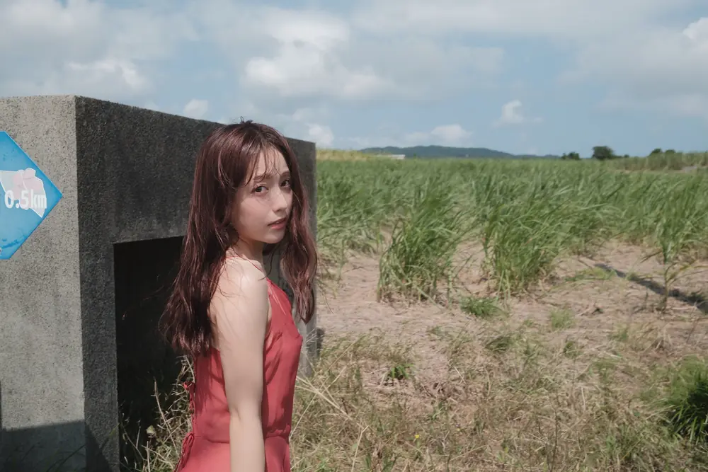 Aimi Yano ยืนในชุดสีแดงท่ามกลางทุ่งหญ้า