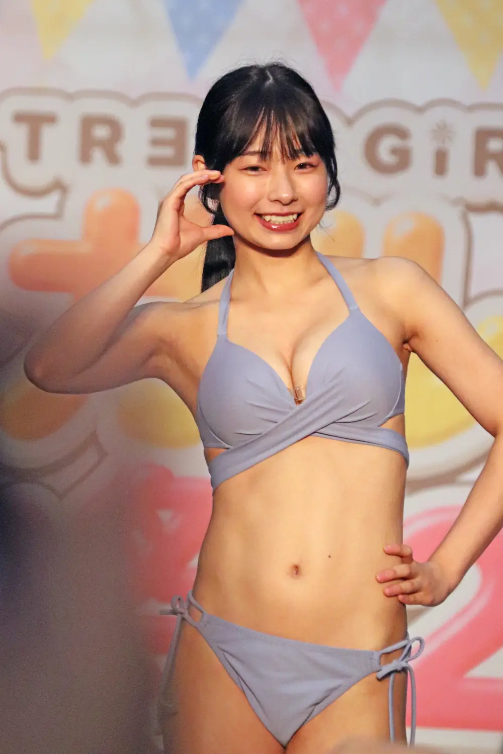 Shizuku Kashiwagi สวมชุดว่ายน้ำสีเทาและยิ้มบนเวทีกิจกรรม