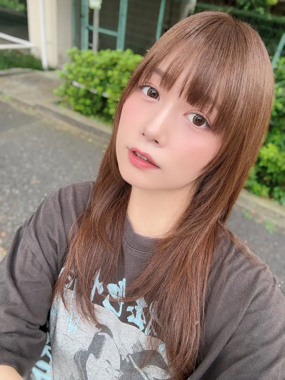 Hikaru Konno สวมเสื้อยืดสีเทาถ่ายภาพบนทางเดินกลางแจ้ง