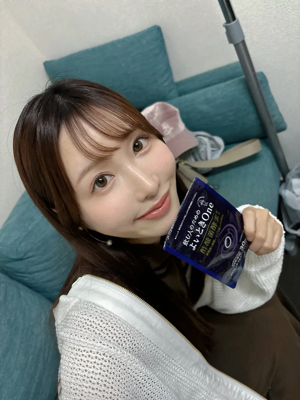 Moe Amatsuka สวมเสื้อถักสีขาวและถือซองสีน้ำเงิน