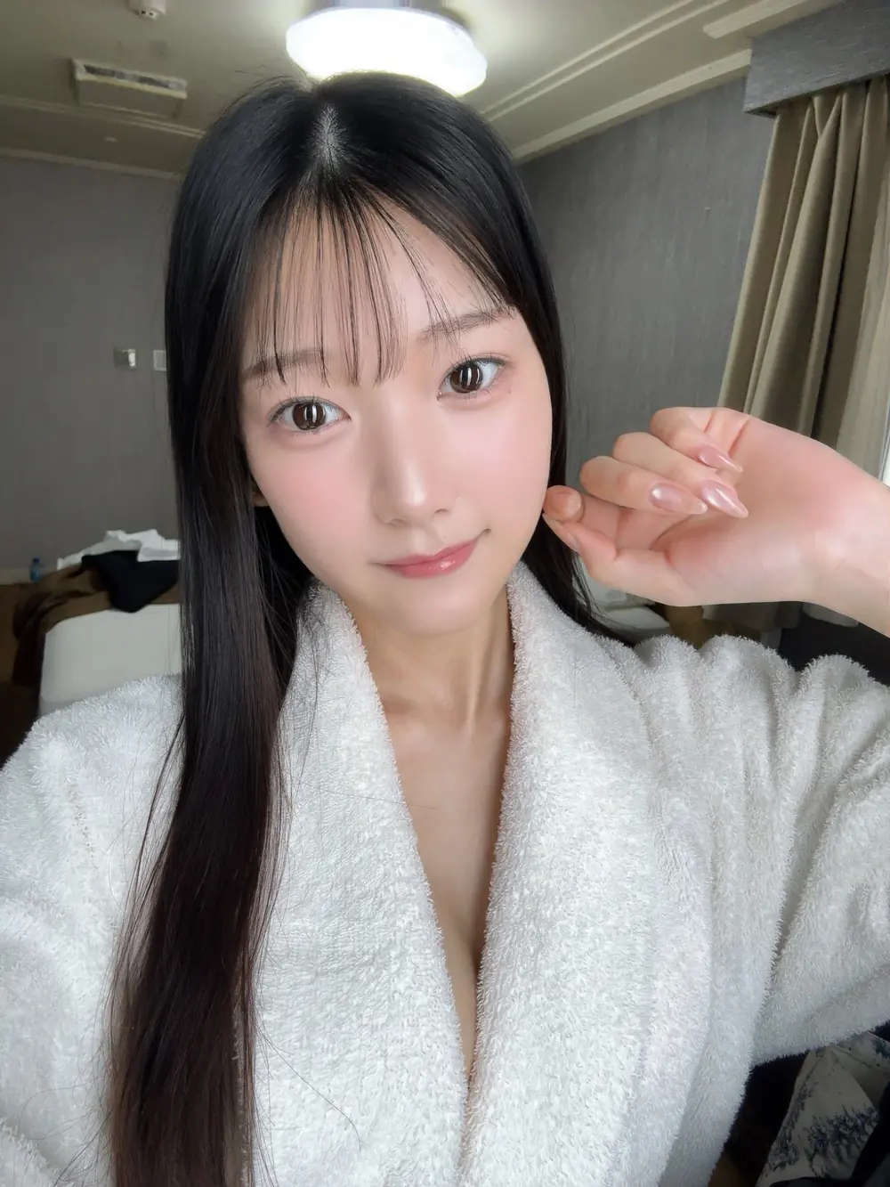 Nanoka Hatsumi สวมเสื้อคลุมสีขาวถ่ายภาพเซลฟี่ในห้อง