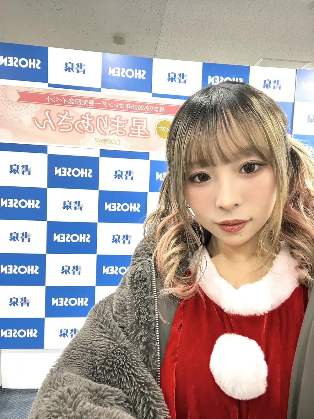 Mahina Amane ในชื่อ Maria Hoshi สวมชุดคริสต์มาสสีแดงขาวหน้าฉากงาน